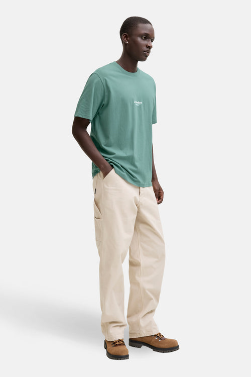 T-shirt à manches courtes bleu de JACK & JONES, porté avec un pantalon beige et des bottines marron.