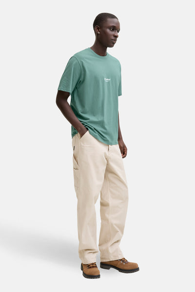 T-shirt à manches courtes bleu de JACK & JONES, porté avec un pantalon beige et des bottines marron.
