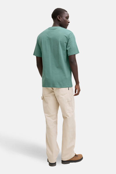 T-shirt à manches courtes bleu par JACK & JONES, porté avec un pantalon beige et des chaussures de randonnée marron.