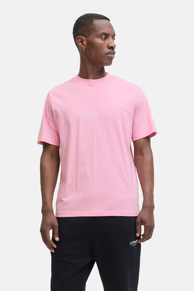 Roze T-shirt met korte mouwen van JACK & JONES, gedragen met een zwarte joggingbroek en zwart-witte sneakers.