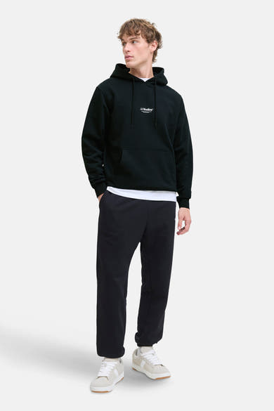 Sweat à capuche noir de JACK & JONES, porté avec un t-shirt blanc et un pantalon de survêtement assorti.