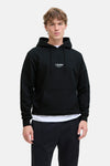Sweat à capuche noir de JACK & JONES porté sur un t-shirt blanc, avec un pantalon de jogging noir.
