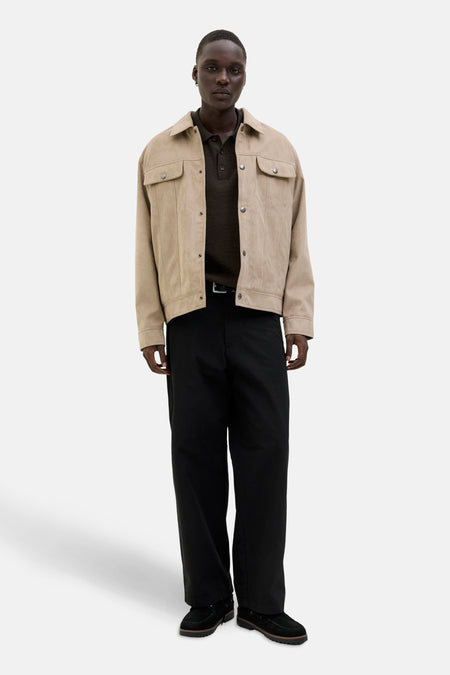 Bruine V-hals trui van JACK & JONES, gedragen met een beige jasje en een wijde zwarte broek.