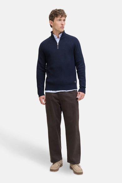 Pull col roulé bleu de JACK & JONES avec fermeture éclair argentée et détails côtelés, porté avec chemise et pantalon marron.