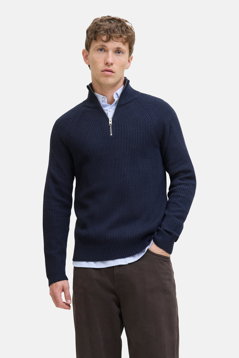 Pull col roulé bleu de JACK & JONES, porté sur une chemise à rayures, avec un pantalon marron.
