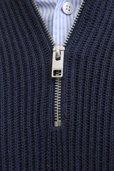 Pull col roulé bleu de JACK & JONES, avec fermeture éclair argentée sur une chemise rayée.