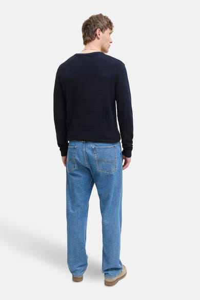 Pull à col rond bleu marine de JACK & JONES, en maille côtelée, porté avec un jean bleu décontracté.