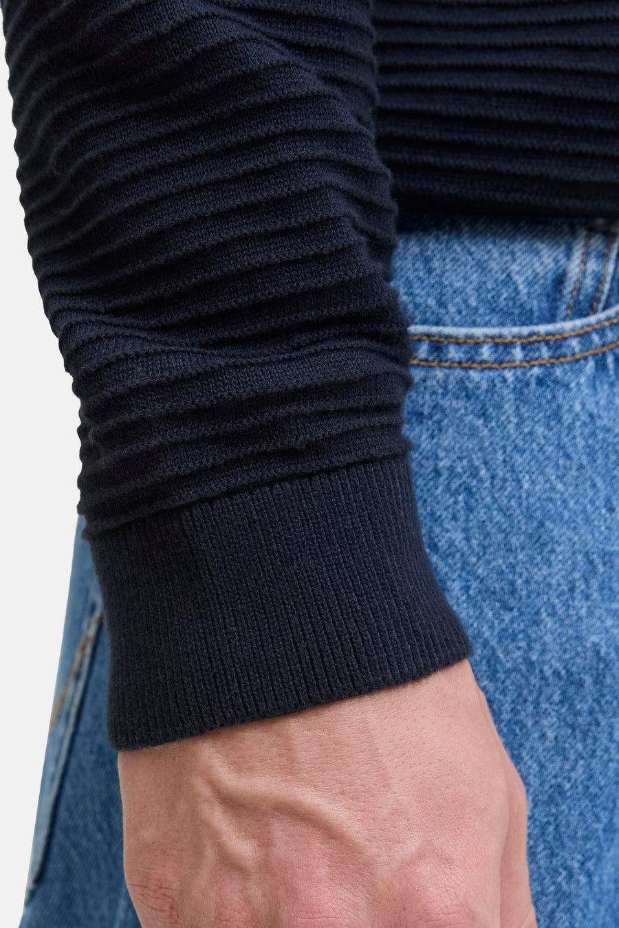 Pull bleu à col rond par JACK & JONES, texture côtelée sur la manche, porté avec un jean.
