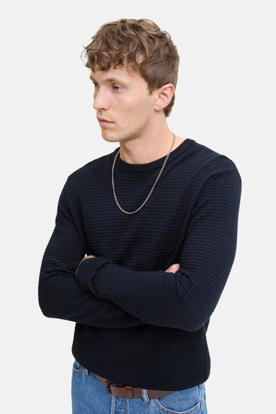 Pull à col rond bleu marine de JACK & JONES, porté avec un jean et un collier argenté.