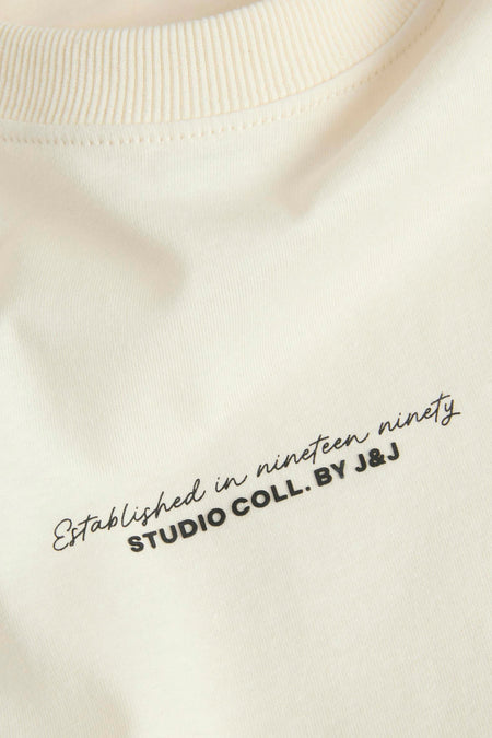 T-shirt écru à manches courtes de JACK & JONES avec inscription stylisée sur le devant.