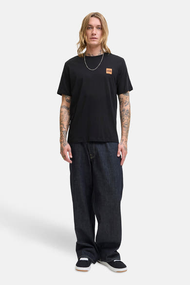 T-shirt à manches courtes noir par ORIGINALS BY JACK & JONES, porté avec un jean ample et un collier argenté.