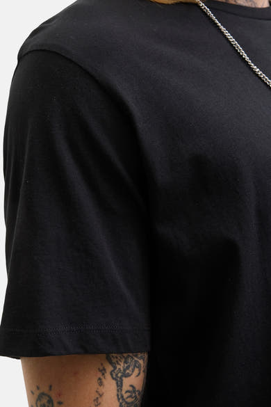 T-shirt noir à manches courtes de Originals by Jack & Jones, détail de chaîne argentée visible et tatouage sur le bras.