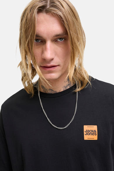 T-shirt noir à manches courtes de ORIGINALS BY JACK & JONES avec logo orange, porté avec un collier argenté.
