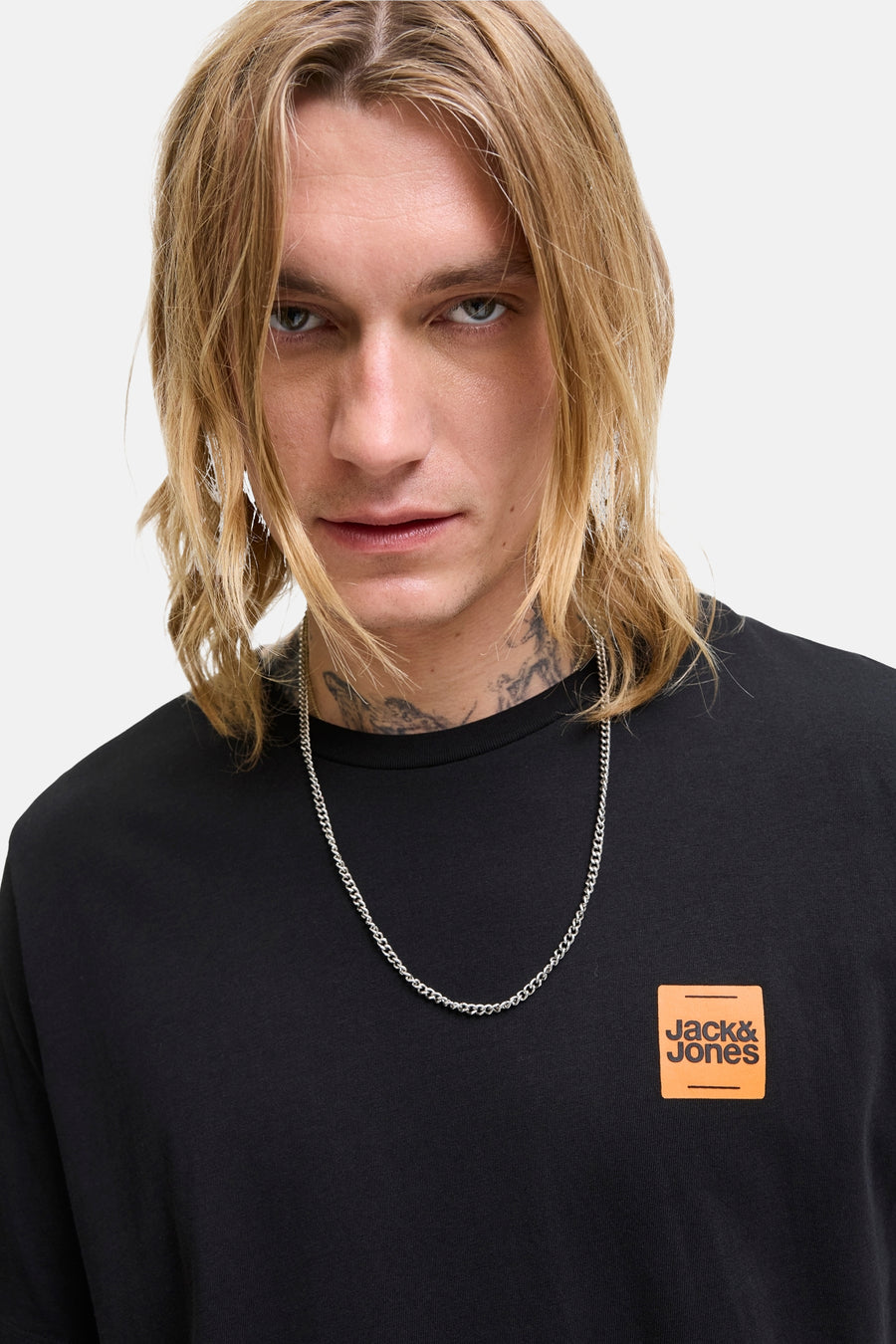 T-shirt noir à manches courtes de ORIGINALS BY JACK & JONES avec logo orange, porté avec un collier argenté.
