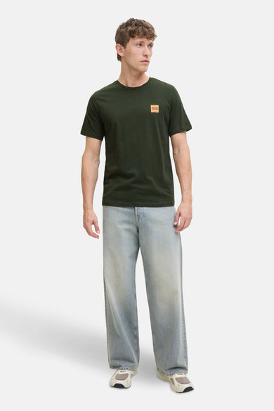 T-shirt à manches courtes vert, de ORIGINALS BY JACK & JONES, avec un logo carré sur la poitrine, porté avec un jean ample bleu.