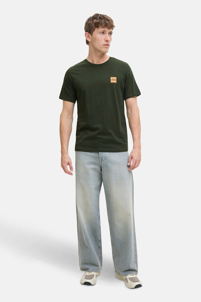 T-shirt à manches courtes vert, de ORIGINALS BY JACK & JONES, avec un logo carré sur la poitrine, porté avec un jean ample bleu.