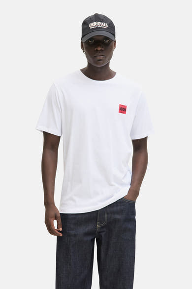 T-shirt blanc à manches courtes de ORIGINALS BY JACK & JONES, porté avec un jean brut et une casquette noire.