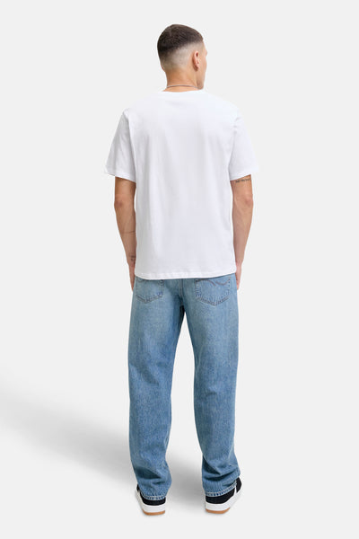 T-shirt à manches courtes blanc de Originals by Jack & Jones, porté avec un jean bleu ample et des baskets noires et blanches.