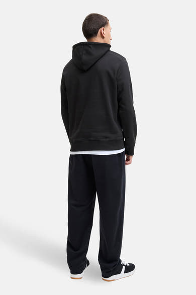Zwarte hoodie van ORIGINALS BY JACK & JONES, gedragen met een wit T-shirt en een joggingbroek.