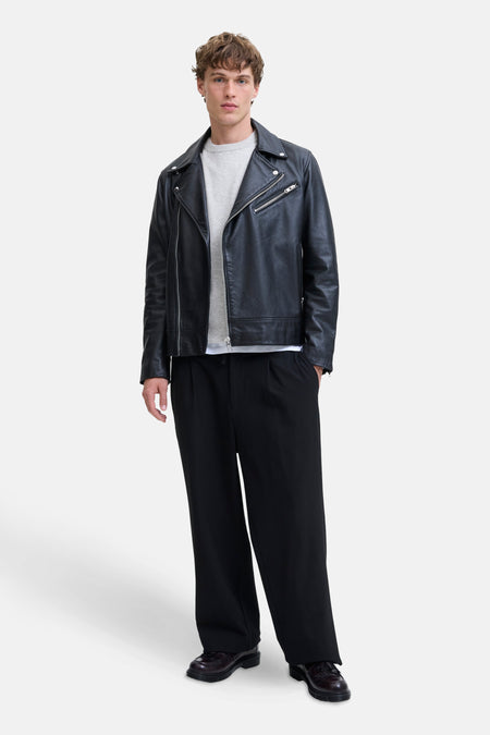 Grijze rondehals trui van PREMIUM by JACK & JONES gedragen onder een zwart leren jack.