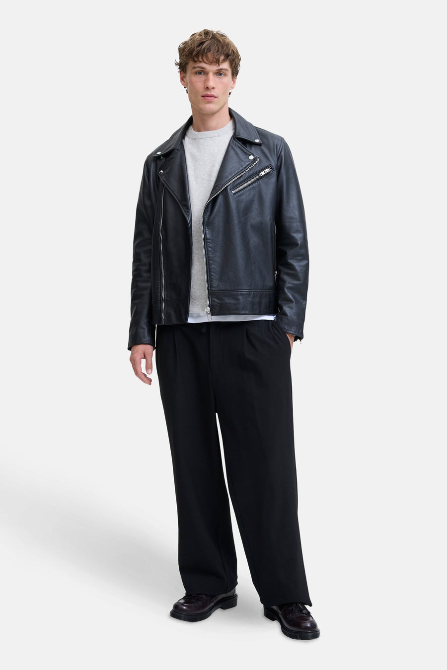 Pull à col rond gris de PREMIUM by JACK & JONES porté sous un blouson en cuir noir.