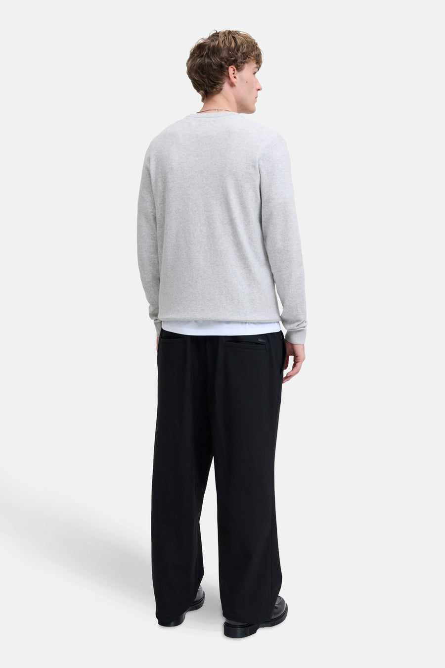 Pull à col rond gris de PREMIUM by JACK & JONES, porté avec un pantalon noir ample et des chaussures en cuir.