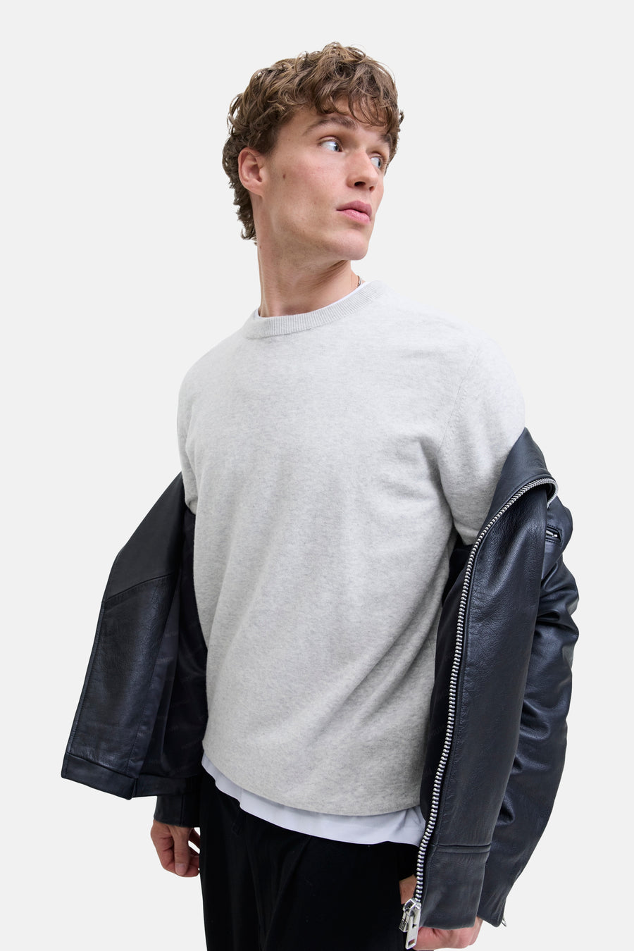 Pull à col rond gris de PREMIUM by JACK & JONES, porté avec une veste en cuir noir ouverte.