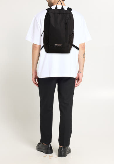 Sac à dos noir by ACCESSORIES BY JACK & JONES porté avec un t-shirt blanc et un pantalon noir.