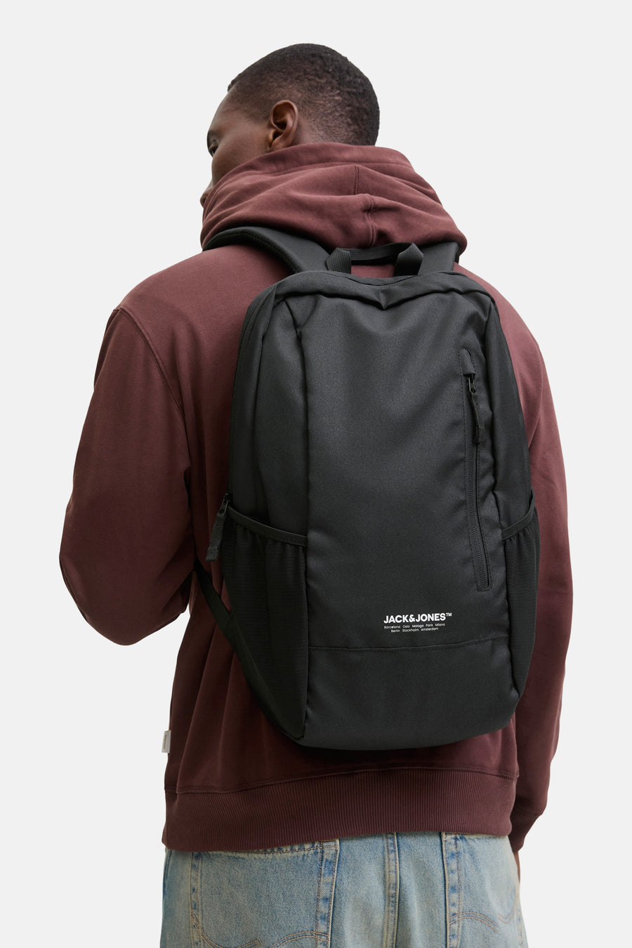 Sac à dos noir de ACCESSORIES BY JACK & JONES, porté avec un sweat à capuche bordeaux et un jean bleu clair, vue de dos.