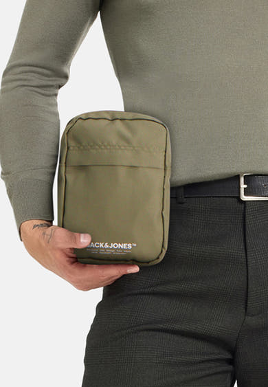Sac à bandoulière kaki par ACCESSORIES BY JACK & JONES, porté avec un pull et un pantalon à carreaux.
