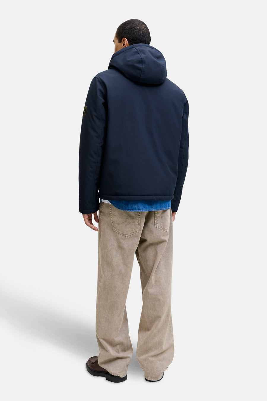 Veste courte bleue par PREMIUM BLUE by JACK & JONES, portée sur une chemise en jean et un pantalon beige.