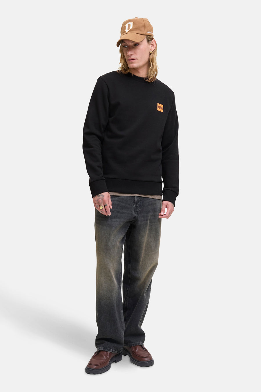 Sweat-shirt noir de ORIGINALS BY JACK & JONES avec un logo carré orange, porté avec un jean délavé et des mocassins marron.

