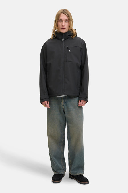Korte zwarte jas van JACK & JONES, gedragen met een wijde jeans en bootschoenen.