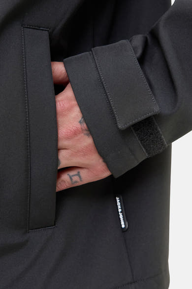 Veste courte noire de JACK & JONES avec une main dans la poche et fermeture velcro au poignet.
