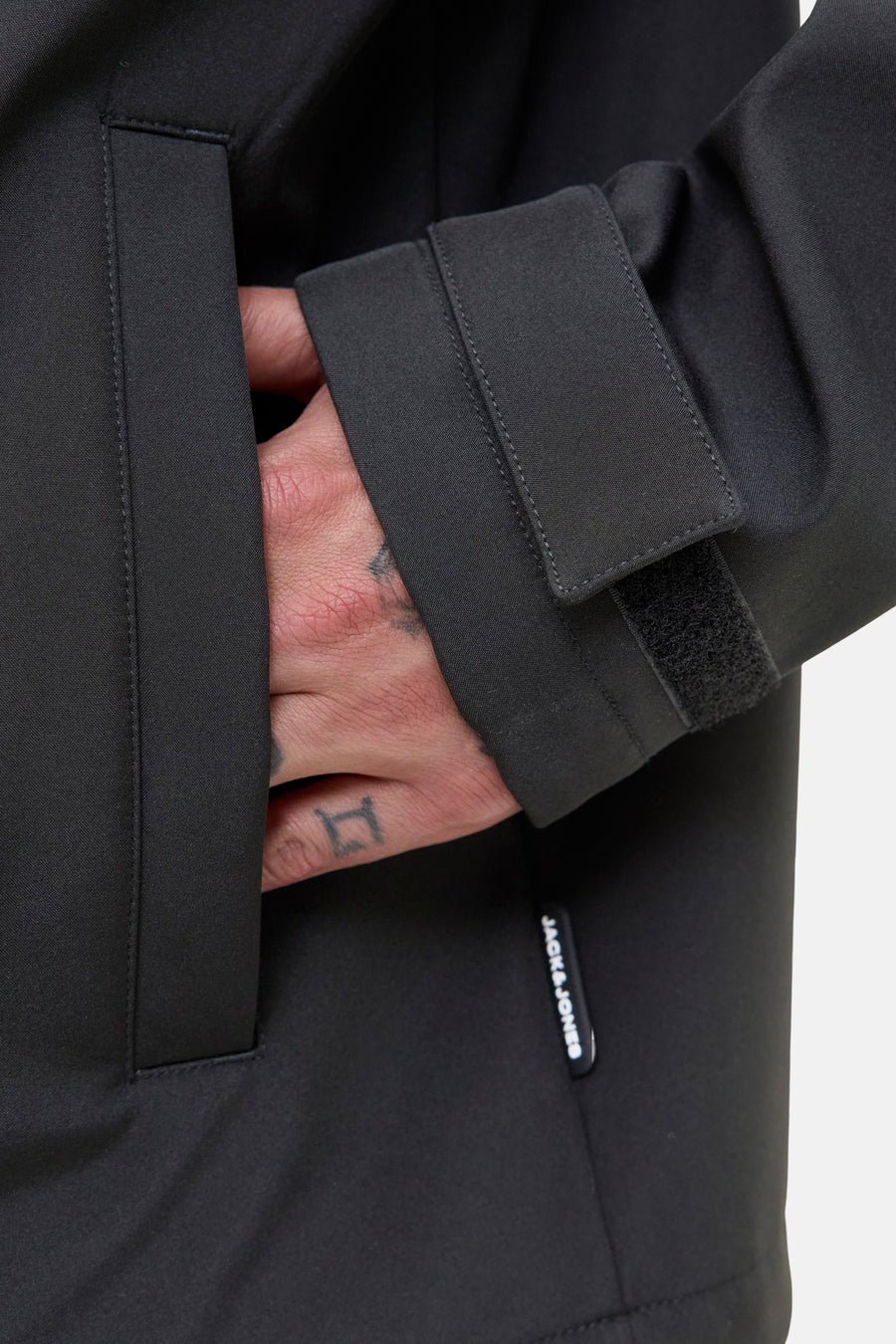 Veste courte noire de JACK & JONES avec une main dans la poche et fermeture velcro au poignet.