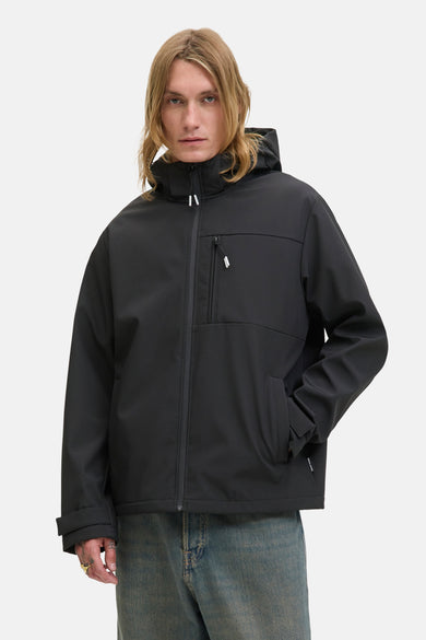 Veste courte noire par JACK & JONES avec une capuche et une fermeture éclair visible, portée avec un jean bleu.