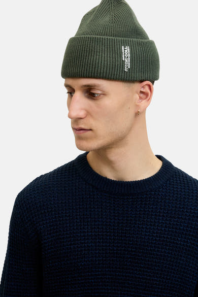 Bonnet vert en maille côtelée de Accessories by Jack & Jones, porté avec un pull bleu marine.