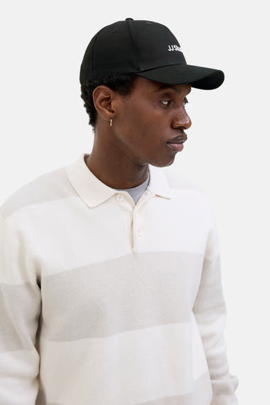 Casquette noire par ACCESSORIES BY JACK & JONES avec logo brodé, portée avec un polo rayé.