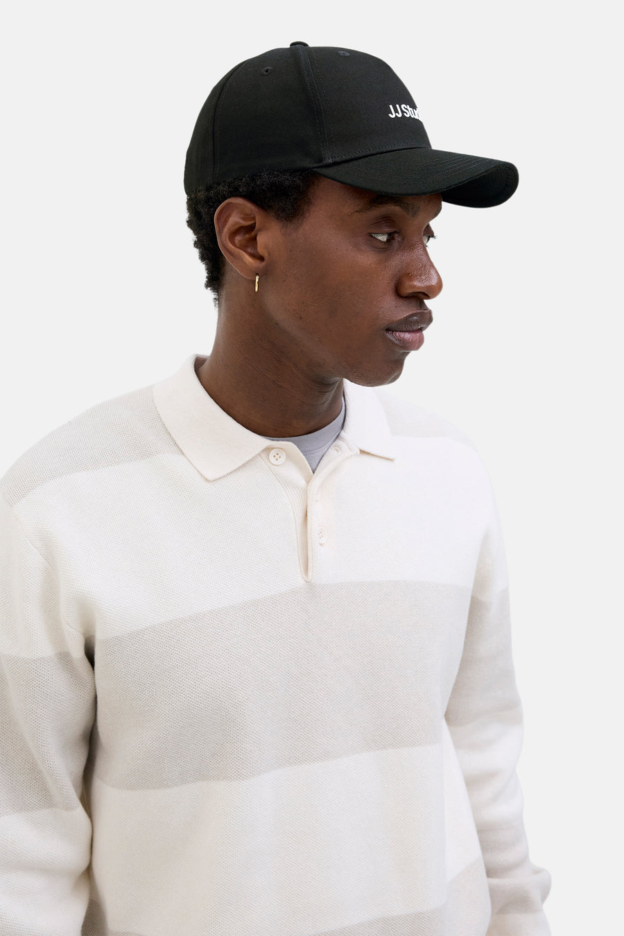 Casquette noire par ACCESSORIES BY JACK & JONES avec logo brodé, portée avec un polo rayé.