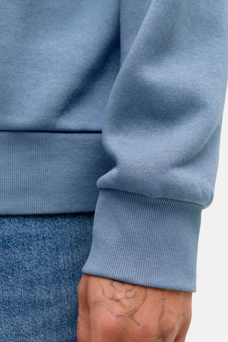 Sweat bleu d'ORIGINALS BY JACK & JONES avec poignet côtelé, porté avec un jean.
