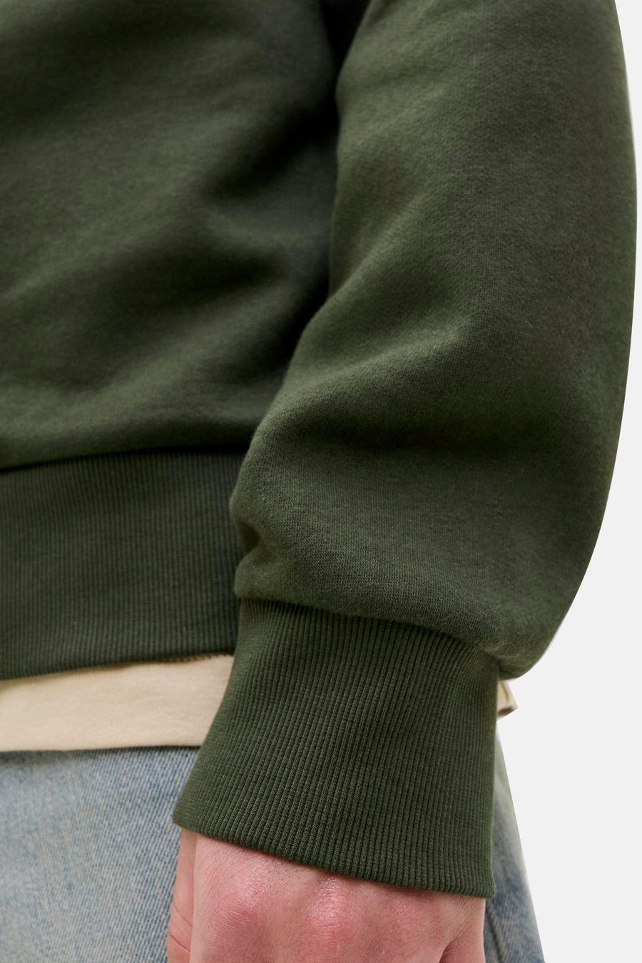 Groene sweater van Originals by Jack & Jones, met geribde boorden, gedragen met een beige T-shirt en een blauwe jeans.