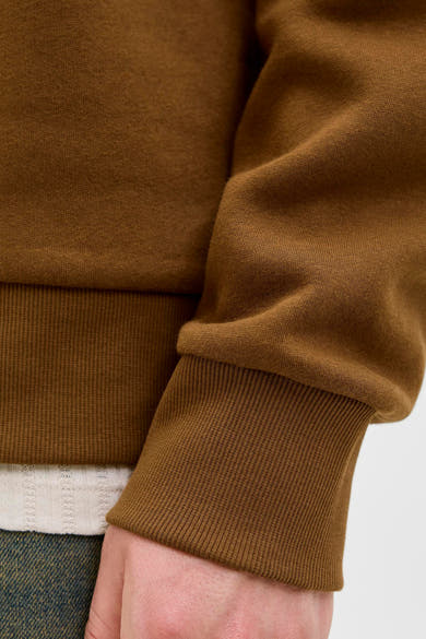Sweat-shirt marron par ORIGINALS BY JACK & JONES, détail côtelé au poignet, avec un t-shirt et un jean en dessous.