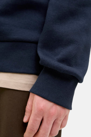 Marineblauwe hoodie van Originals by Jack & Jones, geribbelde details bij de pols, gedragen met een beige T-shirt.