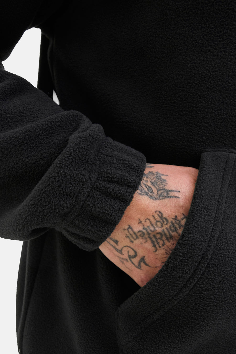Polaire noire par JACK & JONES, avec une texture douce et une manche avec un tatouage visible.
