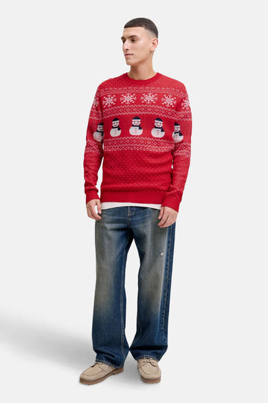 Pull à col rond rouge de JACK & JONES avec motif de bonhommes de neige et flocons, porté avec un jean ample.
