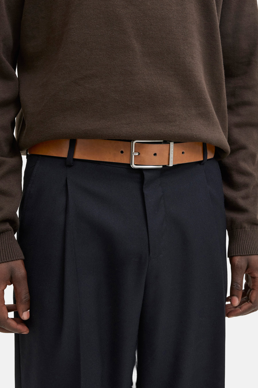 Ceinture marron en cuir, par ACCESSORIES BY JACK & JONES, portée avec un pantalon de ville bleu marine et un pull marron.