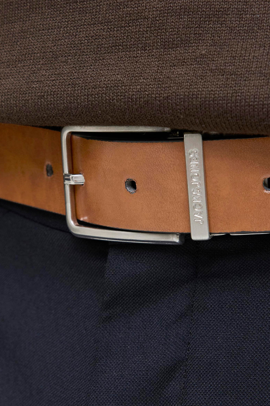 Ceinture marron par ACCESSORIES BY JACK & JONES, boucle argentée, portée avec un pull marron et un pantalon bleu marine.