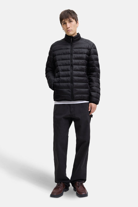 Veste de pluie noire par JACK & JONES, portée avec un pantalon noir et des chaussures marron.