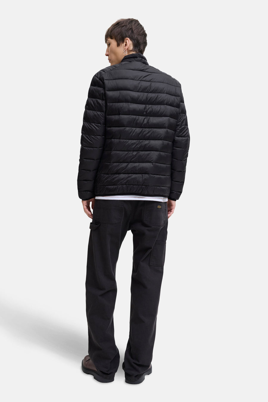 Veste de pluie noire par JACK & JONES, portée avec un t-shirt blanc et un pantalon foncé.