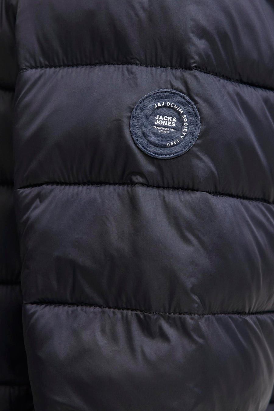Veste de pluie noire par Jack & Jones, avec texture matelassée et logo sur le devant.